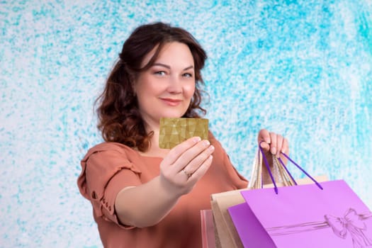 Happy smiling woman holding colourful shopping paper bags shows banking credit card