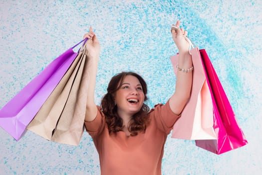 Happy smiling woman at shopping holding colourful paper bags in both hands