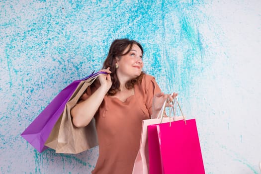 Happy smiling woman at shopping holding colourful paper bags in both hands