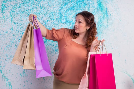 Happy smiling woman at shopping holding colourful paper bags in both hands