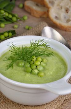 A plate of soup puree of green peas with dill on a table