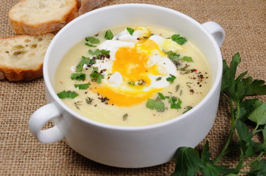 potato cream soup with bacon and poached eggs, herbs, spices