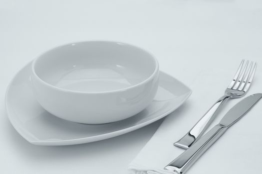 close up view of white plates and utensils on white table