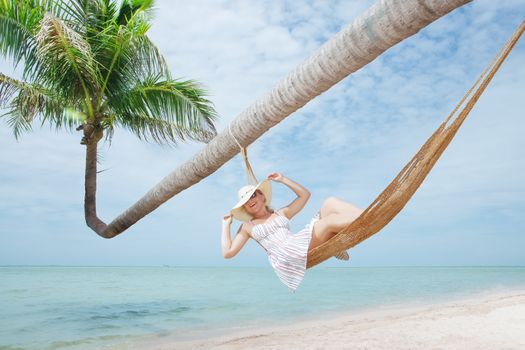 view of nice young lady swinging  in hummock on tropical beach