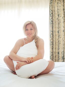 portrait on gorgeous young smiling woman in bedroom environment