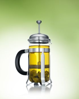 close up view of french press and a cup of green tea on green background