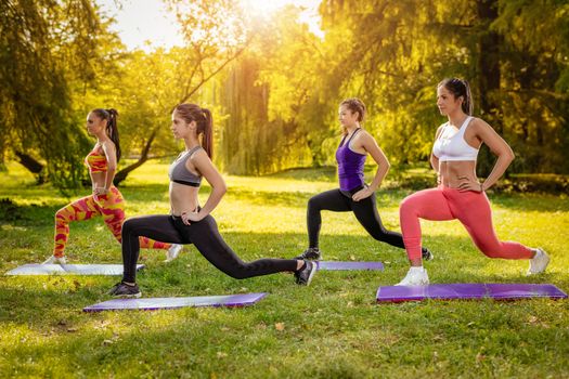 Four beautiful female friends doing exercise in the park. 