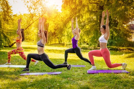 Four beautiful female friends doing exercise in the park. 