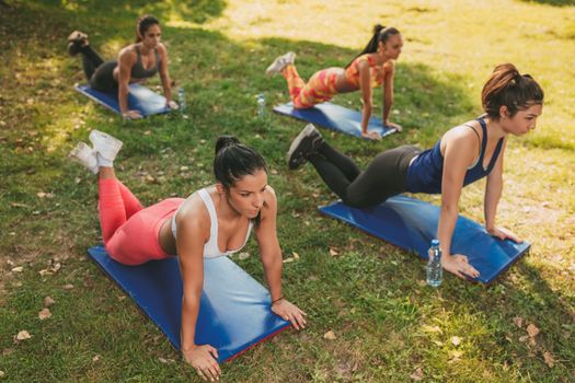 Four beautiful female friends doing exercise in the park. Selective focus. 