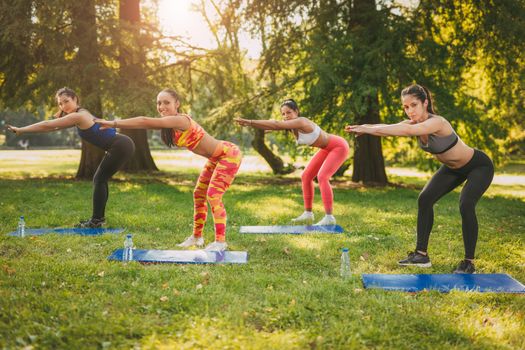 Four beautiful female friends doing exercise in the park. 