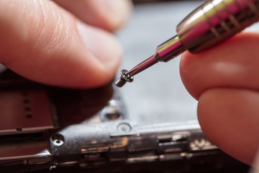 Close-up of a male hands servising broken smartphone.