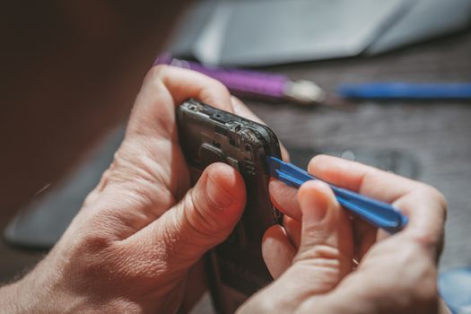 Close-up of a male hands servising broken smartphone.