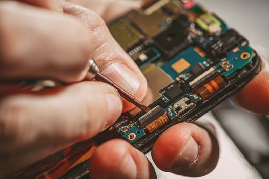 Close-up of a male hands servising broken smartphone.