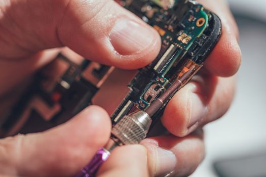 Close-up of a male hands servising broken smartphone.