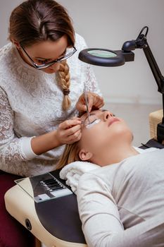 Beautician applying extended eyelashes to model at the beauty salon.