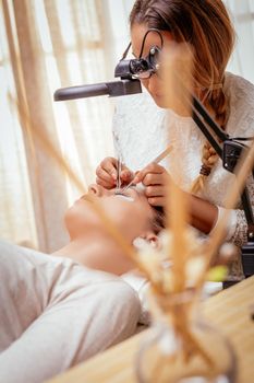 Beautician applying extended eyelashes to model at the beauty salon.