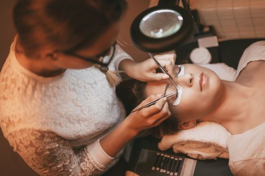 Beautician applying extended eyelashes to model at the beauty salon.