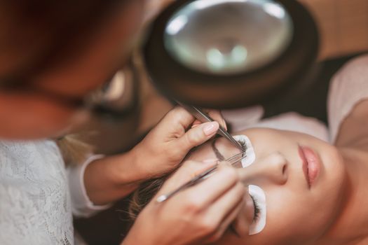 Beautician applying extended eyelashes to model at the beauty salon.