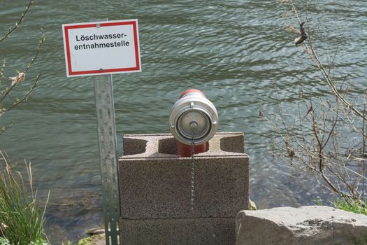 Information board with the inscription in German fire water extraction point. Firefighting Equipment in a river.