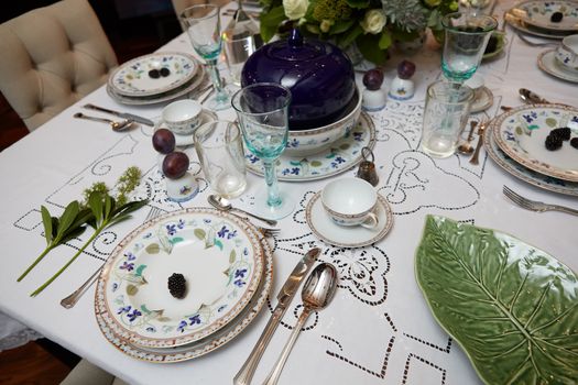 Decorated table ready for dinner. Beautifully decorated table set with flowers, candles, plates and serviettes for wedding or another event in the restaurant.