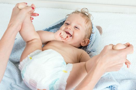 Cute happy beautiful smiling playful child boy with wet hair sitting in hothouse bath light blue fluffy towel white background, horizontal photo.