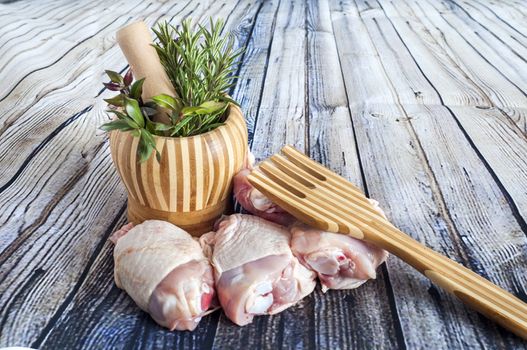 herbs in a mortar and thighs Raw chicken