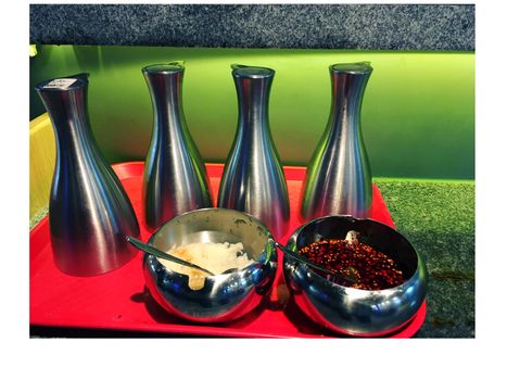 Photo of different sauces and condiments on a table in a cafe food dips and sauces in bottles and two  sauces Bowls with chilli  red pepper, garlic paste 