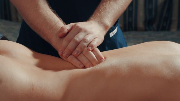 Man's hands massaging woman's back, close up