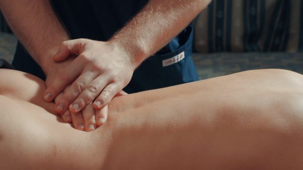 Man's hands massaging woman's back, close up