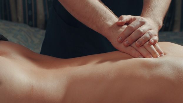 Man's hands massaging woman's back, close up