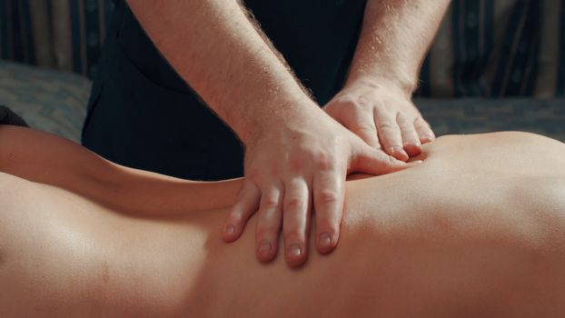 Man's hands massaging woman's back, close up