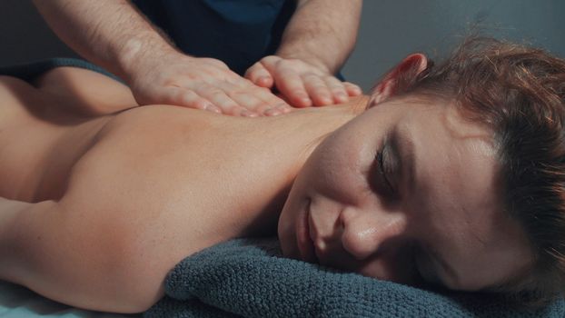 Man's hands massaging woman's back, close up