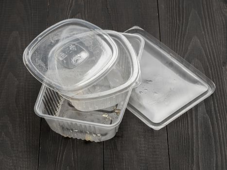 Dirty plastic food container on dark wooden background. Used food box as Garbage. Environmental pollution concept