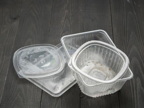 Dirty plastic food container on dark wooden background. Used food box as Garbage. Environmental pollution concept