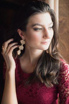 close-up portrait of a beautiful girl in red dress. She touching her hair