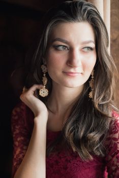 close-up portrait of a beautiful girl in red dress. She touching her hair