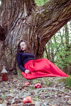 mystical witch woman sitting under a old tree in the forest