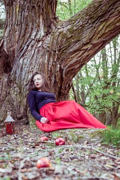 mystical witch woman sitting under a old tree in the forest