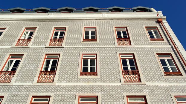 Detail of an old building with portuguese tiles and red and white windows, Lisbon, Portugal