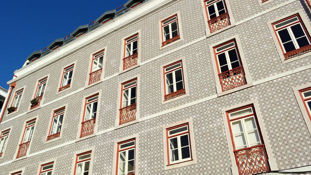 Detail of an old building with portuguese tiles and red and white windows, Lisbon, Portugal