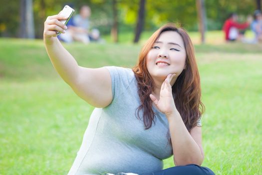 Pretty fat female takes travel selfie at the park