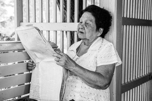 Black and white image of Senior asian woman  Relaxing With Newspaper At Home