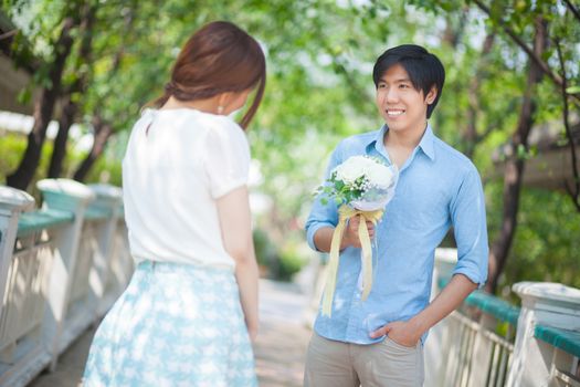 Man ready to give flowers to girlfriend in the park