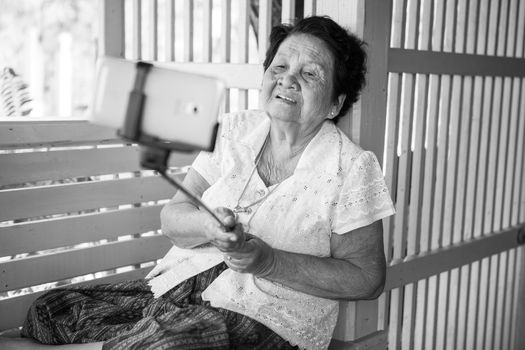 Black and white image of Happy senior woman posing for a selfie at home