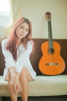 Young beautiful asian woman playing guitar in bed room