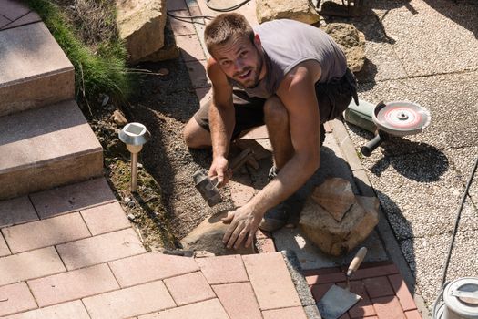 Man Build a dry wall in the garden. In the background, various tools.