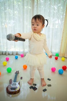 Happy little asian girl with microphone in the home