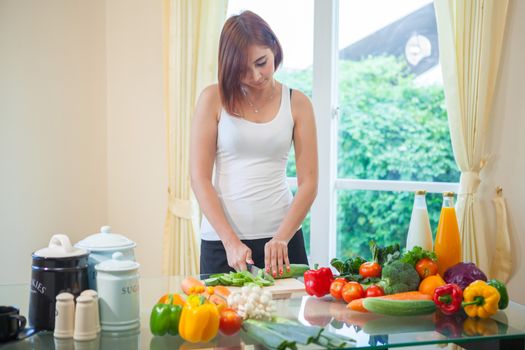 Happy asian woman cooking vegetables green salad in the kitchen