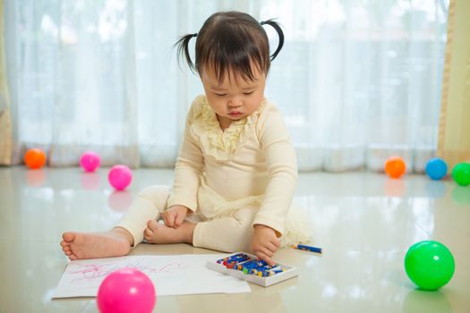 Happy asian baby girl painting with colors in house