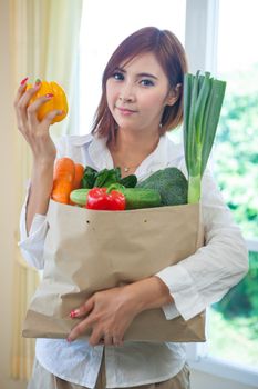 Happy asian woman cooking vegetables green salad in the kitchen